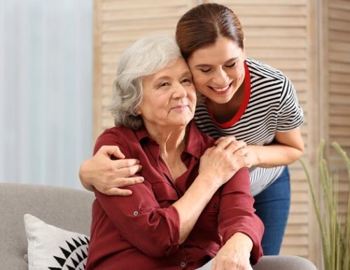 Elderly woman with female caregiver in living room. Space for text